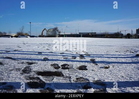 Fußabdrücke im Schnee auf einem leeren Parkplatz, der in den Horizont führt Stockfoto