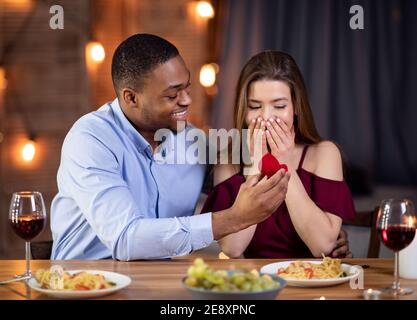 Schöner afrikanischer Mann schlägt seine weiße Freundin vor, ihn zu heiraten Im Restaurant Stockfoto