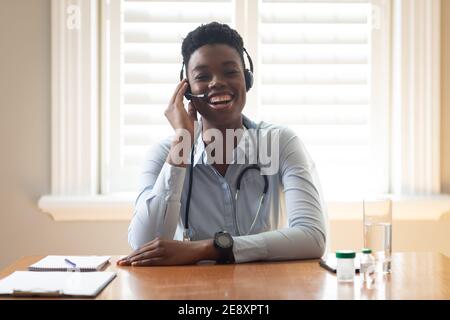 afroamerikanischer Arzt trägt Telefon-Headset sprechen, während eine Videoclip zu Hause Stockfoto