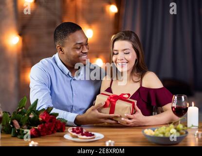 Valentinstag-Feier. Happy Romantic Interracial Paar Essen Im Restaurant, Austausch Von Geschenken Stockfoto