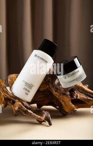 Hautpflegekosmetik der französischen Marke Academie Paris. Creme und Reiniger für die Haut auf Holz Rinde beige Hintergrund in minimalistischem Stil. Redaktionelles Produkt Stockfoto