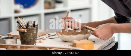 Frau mit Schnitzwerkzeug auf Teller Stockfoto