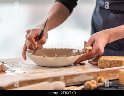 Frau mit Schnitzwerkzeug auf Teller Stockfoto