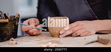 Potter mit Schnitzwerkzeug auf Becher Stockfoto