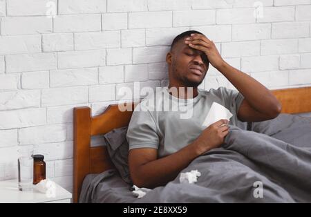 Krank African American Guy Mit Fieber Und Kopfschmerzen Zu Hause Stockfoto