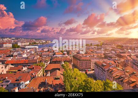 Erstaunlicher dramatischer Himmel mit roten Wolken des Sonnenuntergangs über der Skyline von Genf, französisch-schweizerisch in der Schweiz. Luftaufnahme von Jet d'Eau Brunnen, See Stockfoto