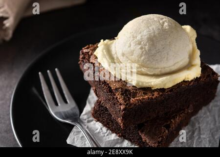 Brownie mit Vanilleeis Schaufel auf schwarzem Hintergrund Stockfoto