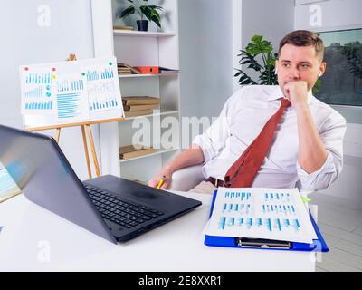 Der männliche Vorgesetzte sieht sich das Webinar an und hört sich das Online-Meeting auf einem Laptop an. Stockfoto