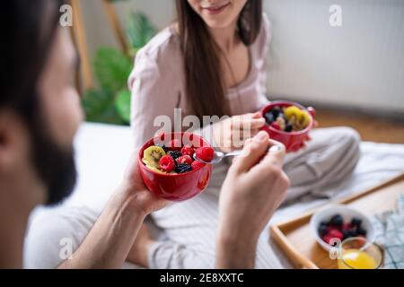 Unbekanntes junges Paar in der Liebe Frühstück auf dem Bett drinnen zu Hause essen. Stockfoto