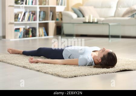 Frau, die Yoga Savasana Pose nach der Übung liegend auf dem Boden zu Hause Stockfoto