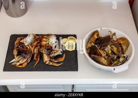 Dungeness Krabbenbeine werden gereinigt und für das Abendessen zubereitet. Krabbenkärtchen und Muscheln werden in einer Schüssel neben ihnen entsorgt. Stockfoto