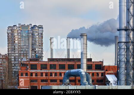 Rauchschornsteine aus der städtischen Thermalstation vor dem Hintergrund von Wohngebäuden schaffen eine schlechte Ökologie in der Stadt. Speicherplatz kopieren. Stockfoto