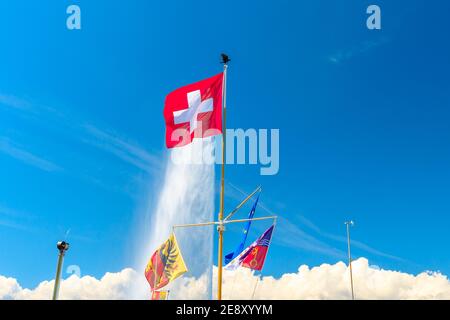 Schweizer Flagge, europäische Flagge und Kanton Genf Flagge und auf dem Hintergrund die berühmteste Attraktion und Symbol der Stadt, Jet d'Eau Brunnen in Leman Stockfoto