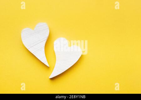 Valentinstag-Konzept. Zwei weiße Holzherzen auf gelbem Hintergrund. Flach liegend, Kopierplatz Stockfoto