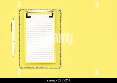 Leeres Clipboard Mockup und weißer Kugelschreiber auf gelbem Hintergrund. Zurück zur Schule, Deadline, Morgenkonzept. Flach liegend, Kopierplatz Stockfoto