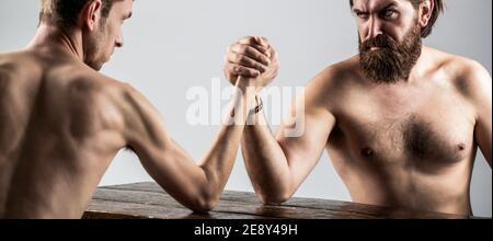 Arme ringen dünne Hand, großer starker Arm im Studio. Zwei Männerhände umklammten Arm Wrestling, stark und schwach, ungleiche Übereinstimmung. Armdrücken. Stark Stockfoto