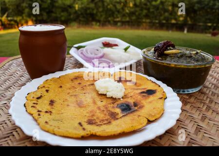 Seitenansicht von Makki di roti und Sarson da saag, Senfblätter Curry und ungesäuertes Maismehlbrot serviert in einer authentischen Art Dorf Stil im Freien Stockfoto