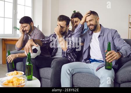 Enttäuschte Fans, die zu Hause auf dem Sofa sitzen und schrecklich zusehen Fußballspiel im Fernsehen Stockfoto