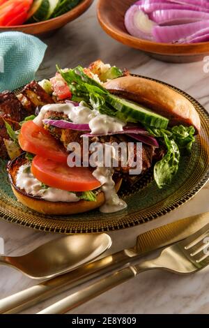 Griechischer gefüllter truthahn-Burger mit Gurkenscheiben und Tsatziki gekrönt Joghurtsauce serviert mit mediterranen Street Cart frittierten Kartoffeln mit Feta-Chees Stockfoto