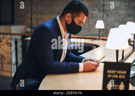 Konzentrierter männlicher Unternehmer starrt auf sein Handy Stockfoto