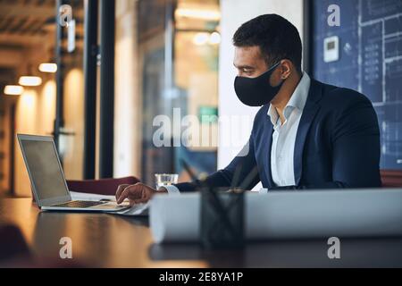 Dunkelhaariger Ingenieur, der den Computer am Arbeitsplatz benutzt Stockfoto