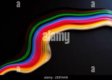 Abstrakte Farbe Welle curl Regenbogen Streifen Papier auf schwarzem Hintergrund Stockfoto