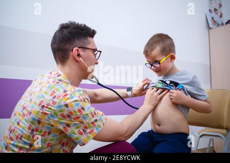 Ein Kind in der Arztpraxis, der Arzt hört auf die Lungen des Jungen. Ärztliche Untersuchung des Kindes Stockfoto