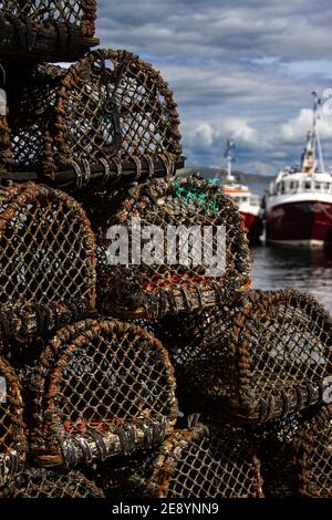 Nahaufnahme eines Stapels von Fischkuttern (Hummer und Krabbenkuttern) mit Fischerbooten im Hintergrund bei Mevagissey, Cornwall Stockfoto