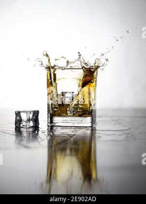 Eiswürfel in ein Whiskey-Glas geben. Whiskey-Spritzer Stockfoto