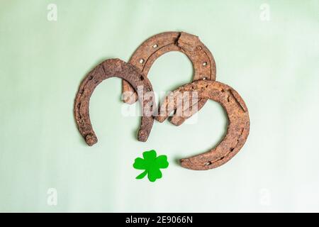 Schlecht abgenutzte Hufeisen mit Filzkleeblatt. Good Luck Symbol, St.Patrick's Day Konzept. Hellgrüner Vinyl-Hintergrund Stockfoto