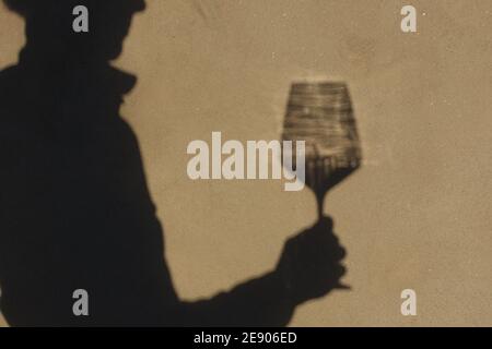 Schatten an der Wand einer Sommelierin allein mit einem Glas Wein. Mit einem gass of Wine Konzept Stockfoto