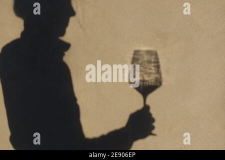 Schatten an der Wand einer Sommelierin allein mit einem Glas Wein. Mit einem gass of Wine Konzept Stockfoto