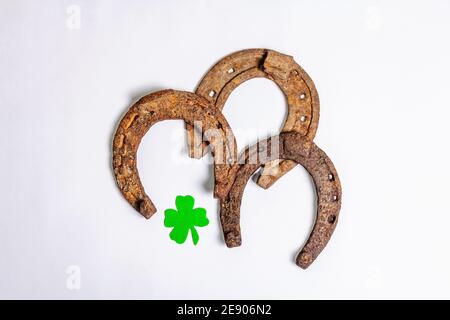 Schlecht abgenutzte Hufeisen mit einem Filzkleeblatt isoliert auf weißem Hintergrund. Good Luck Symbol, St.Patrick's Day Konzept Stockfoto