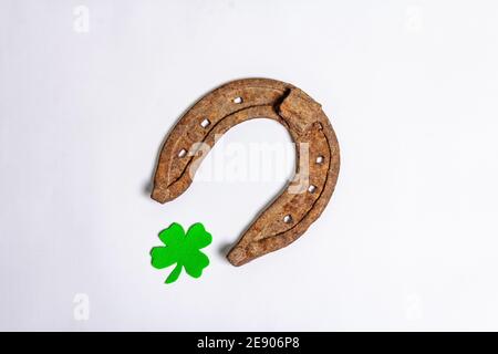 Schlecht abgenutzte Hufeisen mit einem Filzkleeblatt isoliert auf weißem Hintergrund. Good Luck Symbol, St.Patrick's Day Konzept Stockfoto