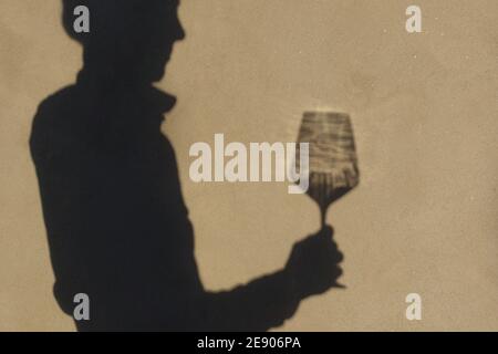 Schatten an der Wand einer Sommelierin allein mit einem Glas Wein. Mit einem gass of Wine Konzept Stockfoto