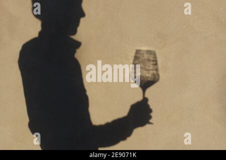 Schatten an der Wand einer Sommelierin allein mit einem Glas Wein. Mit einem gass of Wine Konzept Stockfoto