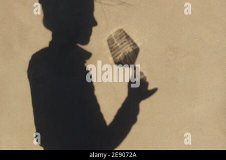 Schatten an der Wand einer Sommelierin allein mit einem Glas Wein. Mit einem gass of Wine Konzept Stockfoto