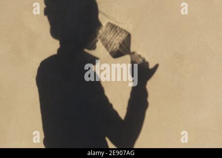 Schatten an der Wand einer Sommelierin allein mit einem Glas Wein. Mit einem gass of Wine Konzept Stockfoto