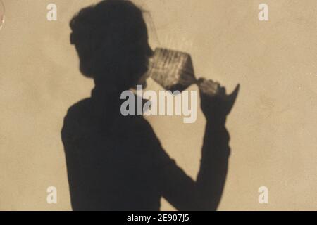 Schatten an der Wand einer Sommelierin allein mit einem Glas Wein. Mit einem gass of Wine Konzept Stockfoto