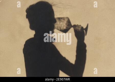 Schatten an der Wand einer Sommelierin allein mit einem Glas Wein. Mit einem gass of Wine Konzept Stockfoto