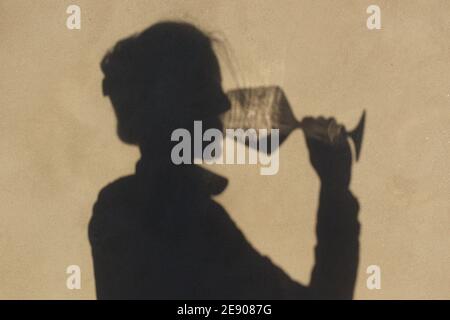 Schatten an der Wand einer Sommelierin allein mit einem Glas Wein. Mit einem gass of Wine Konzept Stockfoto