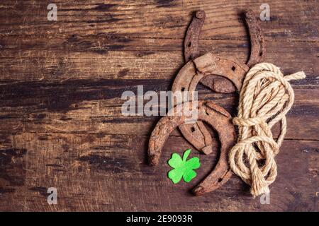 Schlecht abgenutzte Hufeisen, Seil und Filzkleeblatt. Good Luck Symbol, St.Patrick's Day Konzept. Vintage Holzbretter Hintergrund Stockfoto