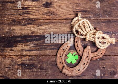 Schlecht abgenutzte Hufeisen, Seil und Filzkleeblatt. Good Luck Symbol, St.Patrick's Day Konzept. Vintage Holzbretter Hintergrund Stockfoto