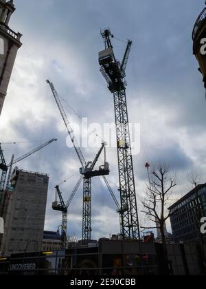 Hohe Turmdrehkrane auf einer Baustelle in London verkrampften sich an einem trüben, bewölkten Wintertag im Februar gegen einen bewölkten Himmel Stockfoto