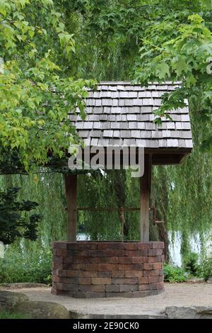 Ein Ziegel, der sich gut wünscht, mit einem Holzschingeldach, umgeben von einer weinenden Weide, einem Ahorn und einem Polarbaum in Janesville, Wisconsin, USA Stockfoto