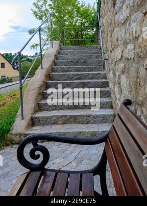 Vertikale Aufnahme einer alten Treppe und einer Holzbank in einem kleinen Dorf Neudenau, Deutschland Stockfoto