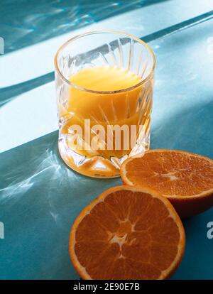 Glas frisch gepressten Orangensaft isoliert auf türkisblau Hintergrund und Sonnenstrahlen Stockfoto