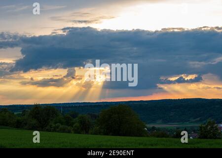 Sonnenuntergang mit Wolken über grünem Feld in Neudenau, Deutschland Stockfoto
