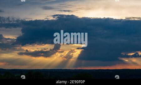 Schöner Sonnenuntergang mit Sonnenstrahlen, die durch Wolken scheinen in Neudenau, Deutschland Stockfoto