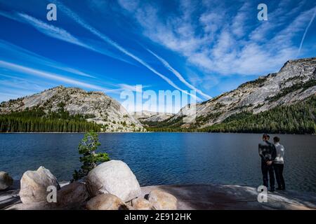 Junges Paar genießt Blick auf Tenaya See in Yosemite, USA: Berglandschaft mit Spiegelsee umgeben von hohen Gipfeln Stockfoto